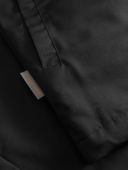 Yksityiskohtakuva mustan naisten Pyry talvitakin sivutaskusta ja sivusaumassa olevasta Image Wearin tuotemerkistä.