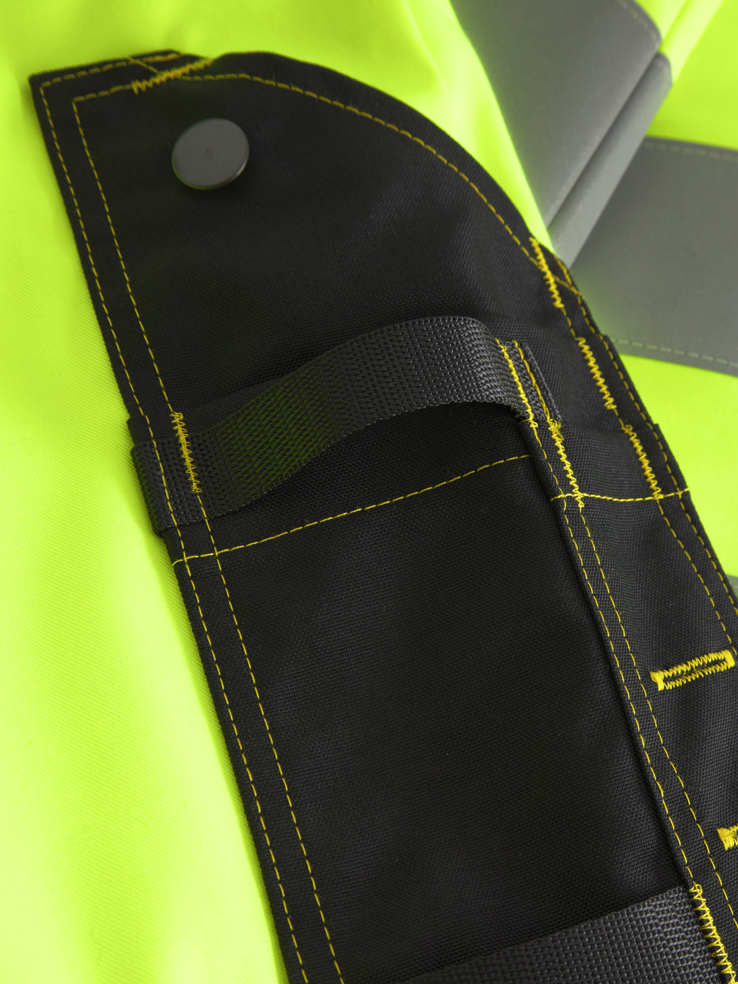 Yksityiskohtakuva näkyvien keltaisten talvihousujen tarviketaskusta. 