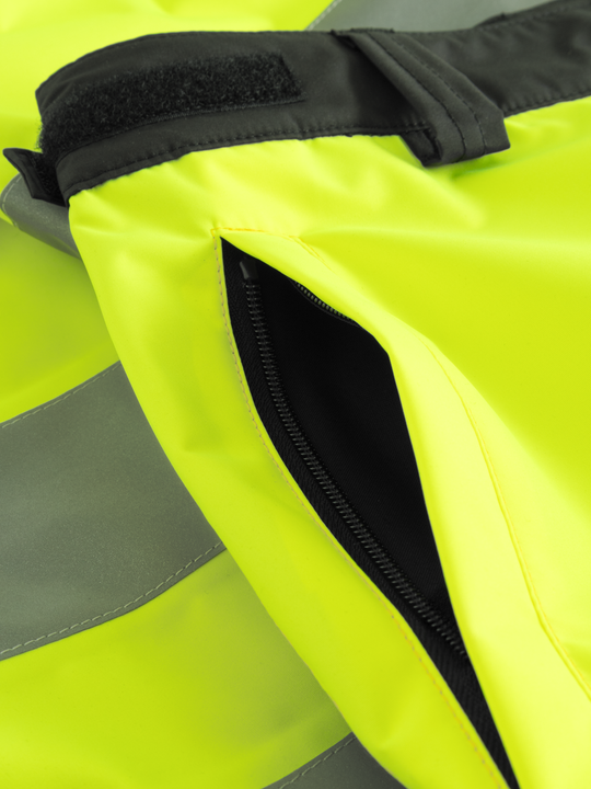 Yksityiskohtakuva keltaisten varoituskuorihousujen vetoketjullisesta sivutaskusta. 