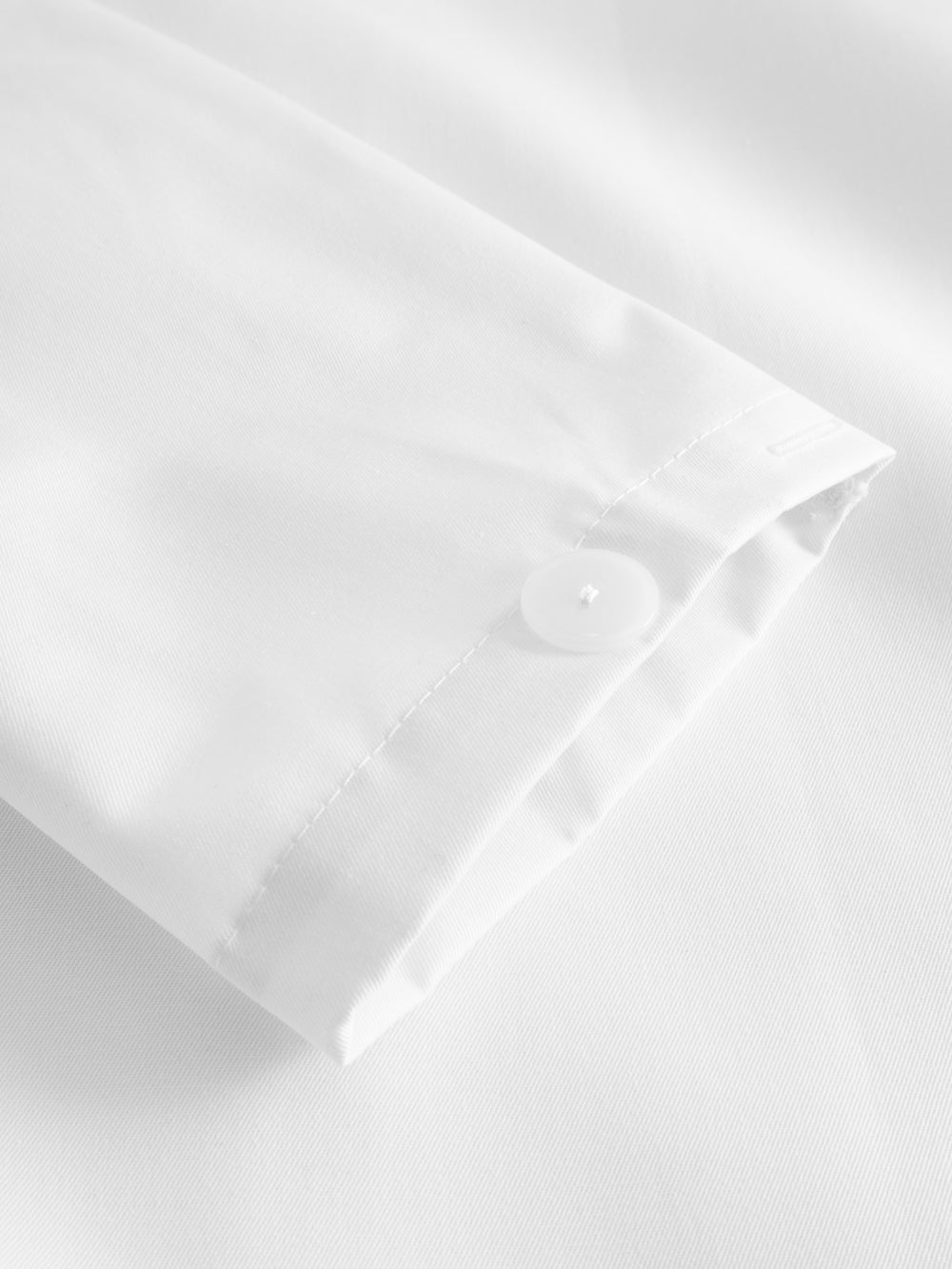 Yksityiskohtakuva valkoisen työtakin hihansuusta. 