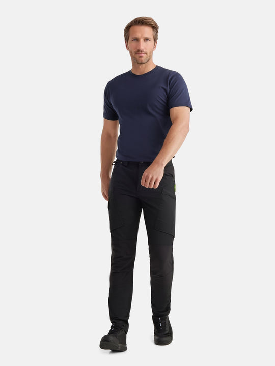 Kuvassa miesmallilla tummansininen unisex t-paita ja mustat joustavat reisitaskuhousut Image Wearin mallistosta. Jalassa mallilla on mustat Sievin Fly fresh-työlenkkarit. 