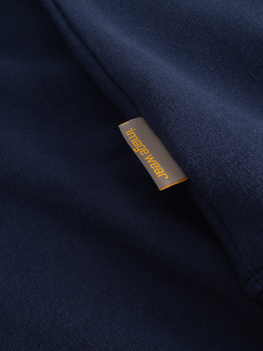 Yksityiskohtakuva tummansinisen collegepaidan sivusaumasta ja Image Wearin tuotemerkistä. 