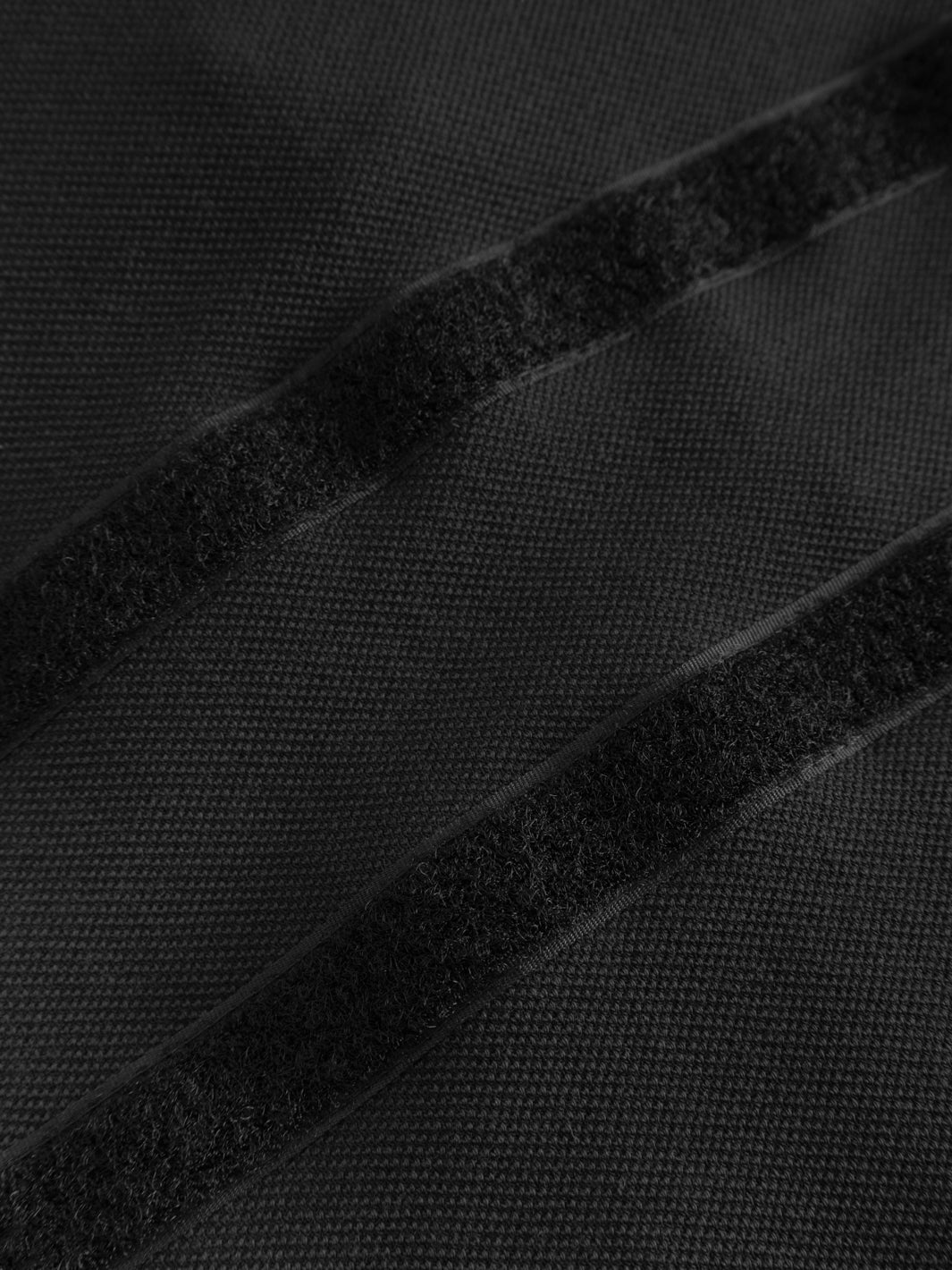 Yksityiskohtakuva mustan vartijan pikeepaidan tarrapaikoista selässä. 