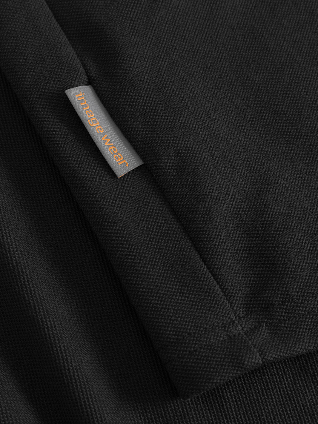Yksityiskohtakuva mustan vartijan pikeepaidan sivusaumassa olevasta Image Wearin tuotemerkistä. 