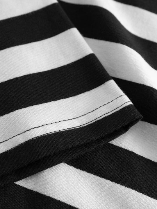 Yksityiskohtakuva mustavalkoraidallisen trikoopaidan helmasta. 