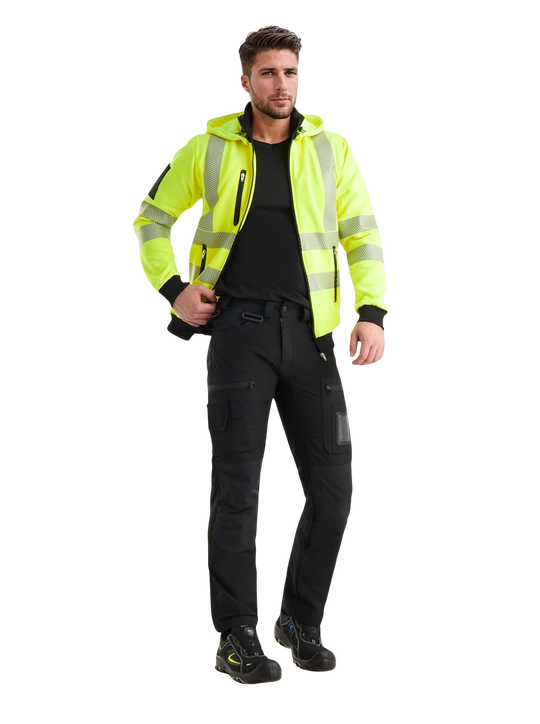 Kuvassa miesmallilla päällä Image Wearin keltainen varoitushuppari, musta t-paita sekä mustat joustoreisitaskuhousut. Jalassa mallilla on Sievin Roller- turvajalkineet. 