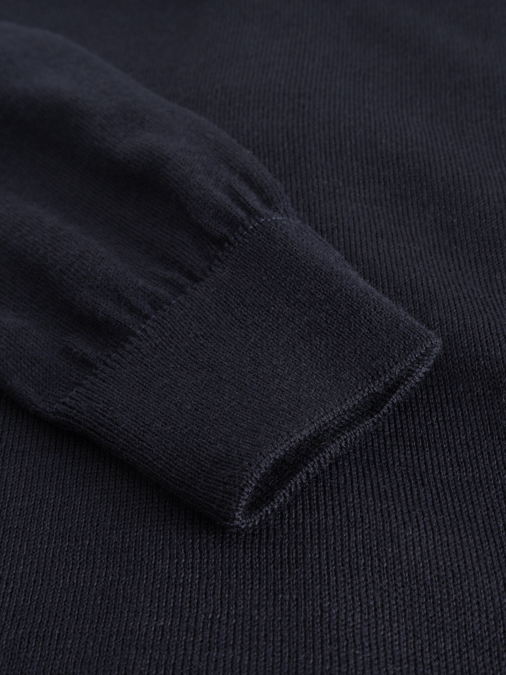 Yksityiskohtakuva tummansinisen neuletakin hihansuun resorista.