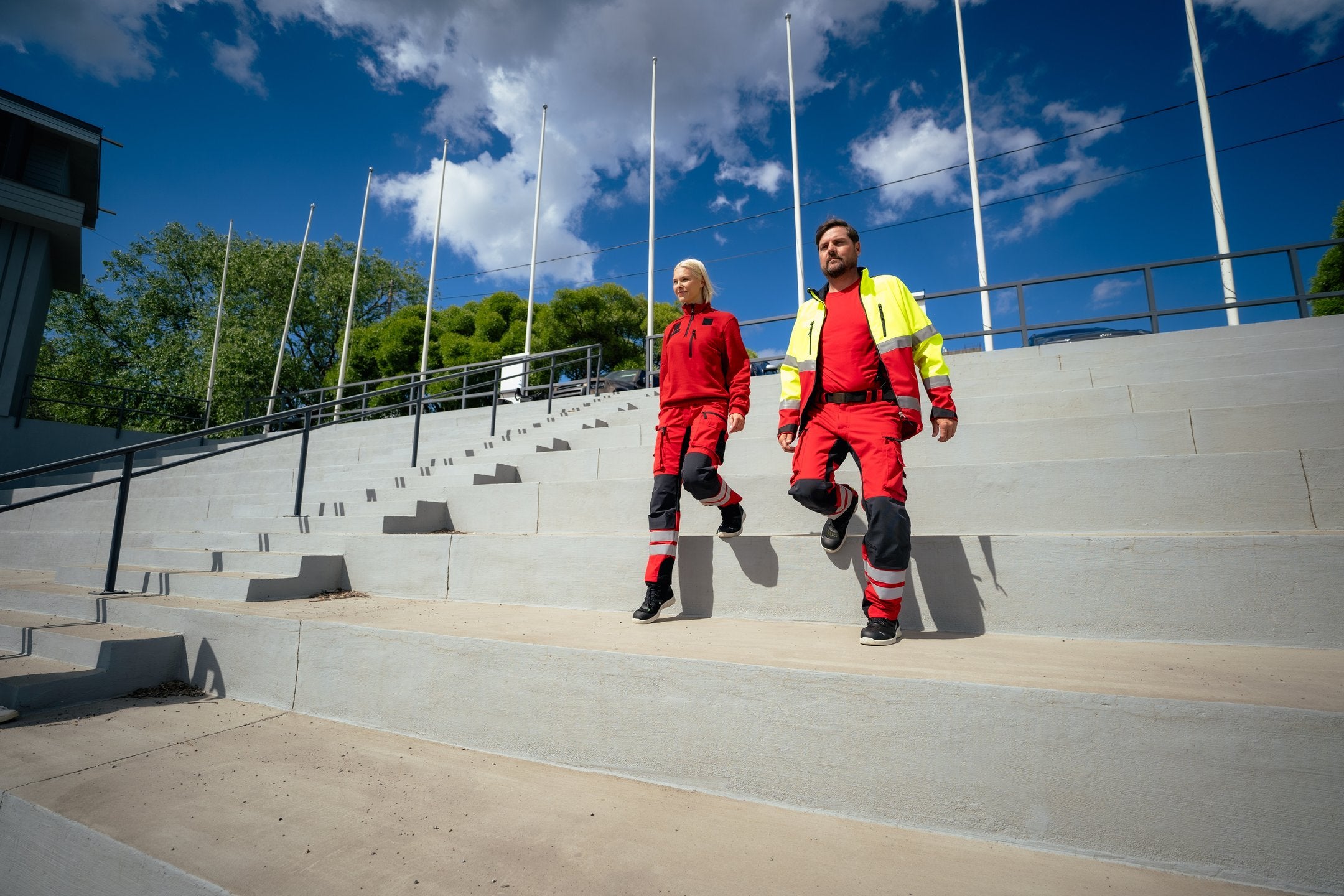 Kuvassa mies ja nainen laskeutuvat portaita ulkona. Molemmilla on päällään Image Wearin ensihoidon työvaatteet sekä jalassa Sievin turva-ja työkengät. 