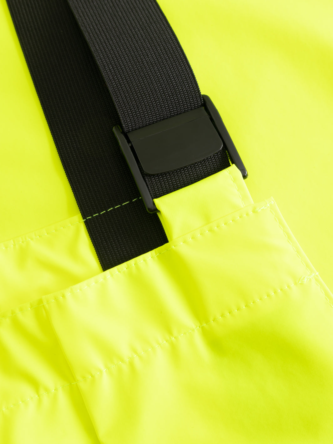 Yksityiskohtakuva keltaisten varoitussadehaalarien säädettävästä joustinolkaimista. 