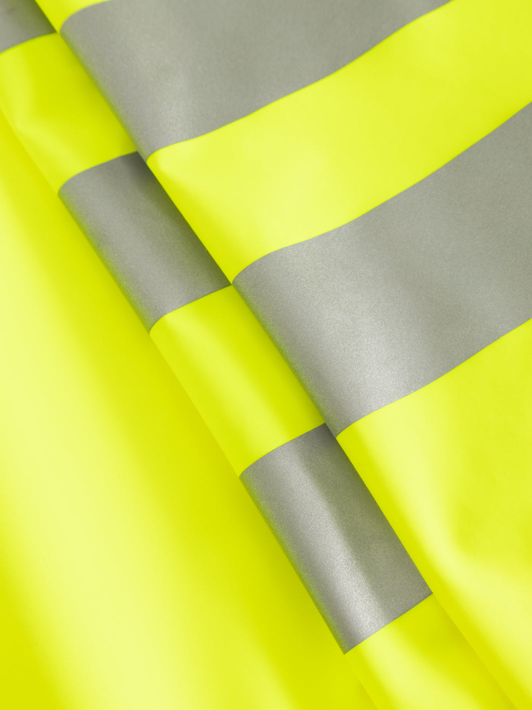 Yksityiskohtakuva keltaisten varoitussadehaalarien heijastinnauhoista. 