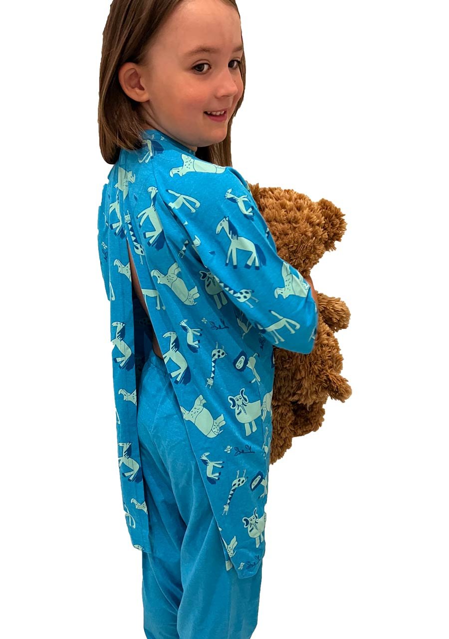 Kuvassa tytöllä sininen lasten kuviollinen pyjamapaita ja yksiväriset pyjamanhousut. 