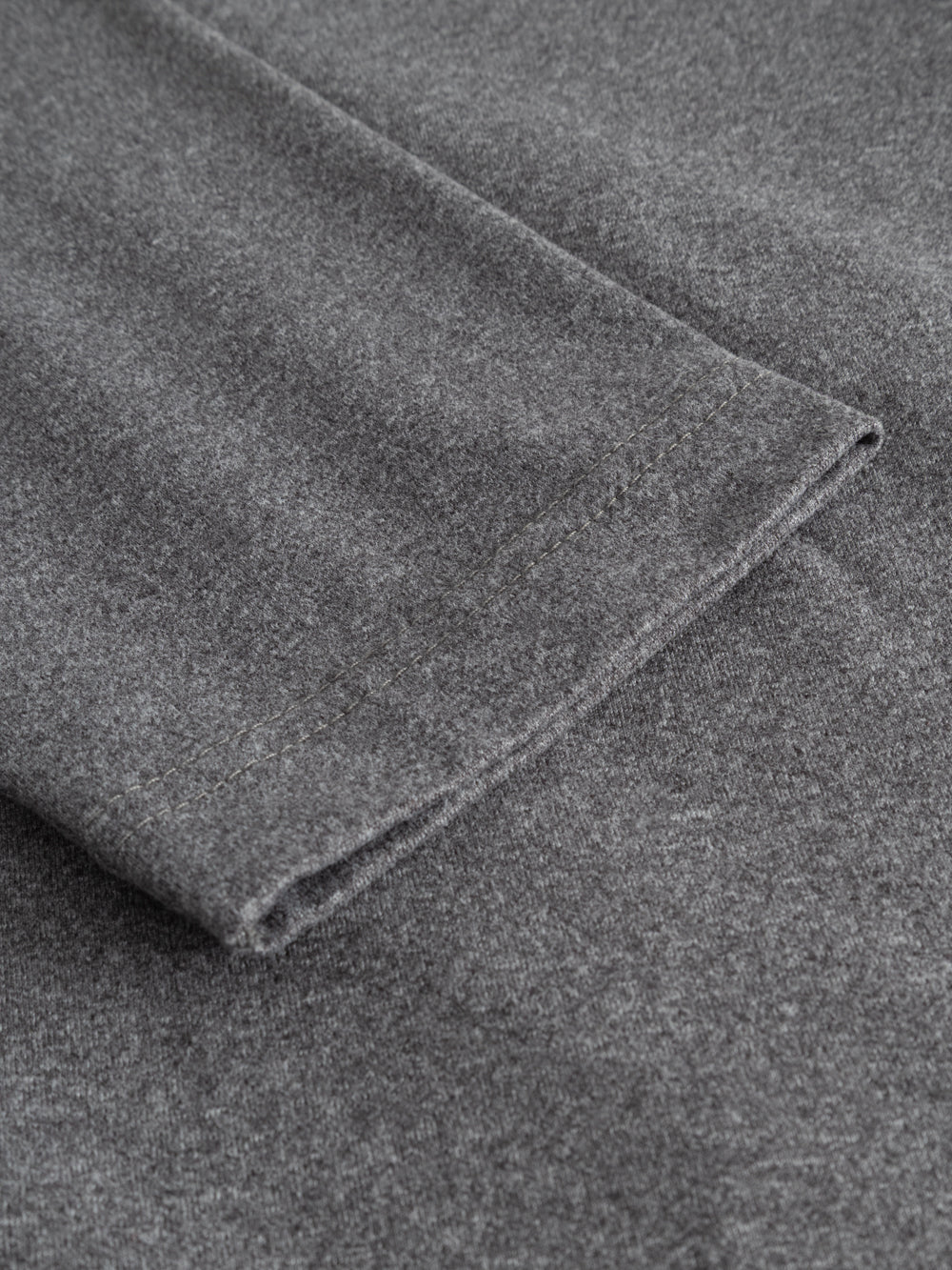 Yksityiskohtakuva harmaan mekon hihansuusta. 